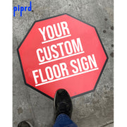 Custom STOP floor decal with "Your Custom Floor Sign" placeholder text  on a warehouse floor