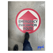 Emergency evacuation floor sign with pedestrian traffic over sign to show durability